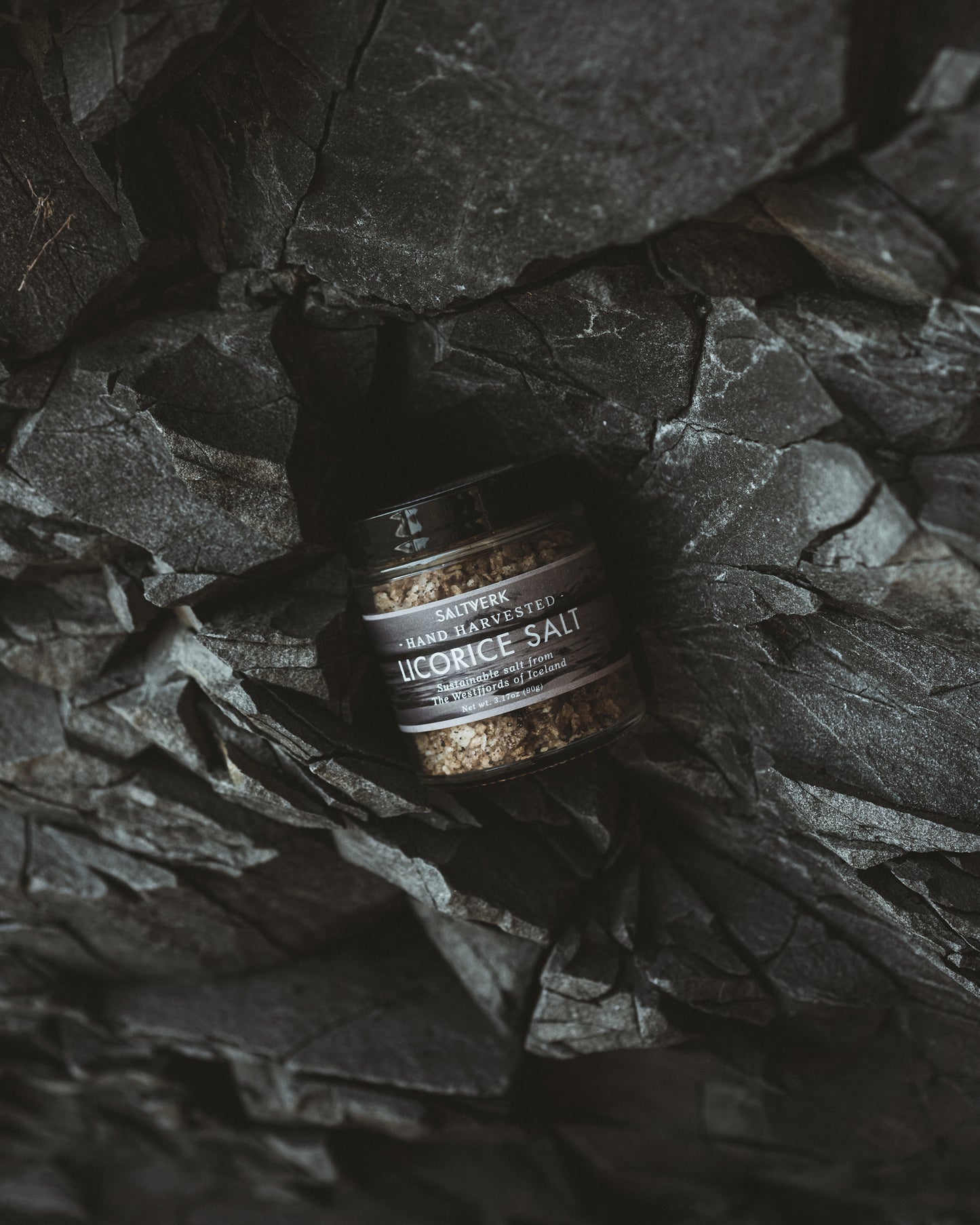 Jar of licorice salt on a dark stone surface