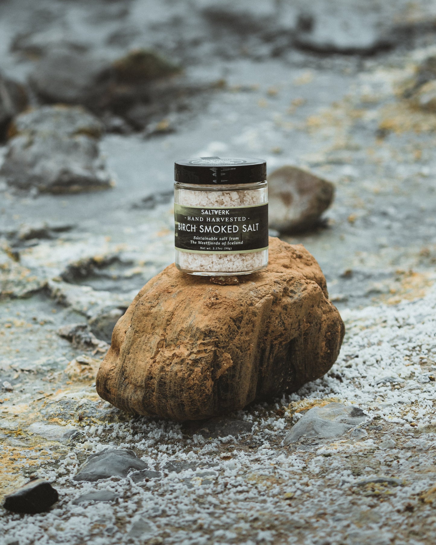 Jar of smoked salt on a rock with a rocky background