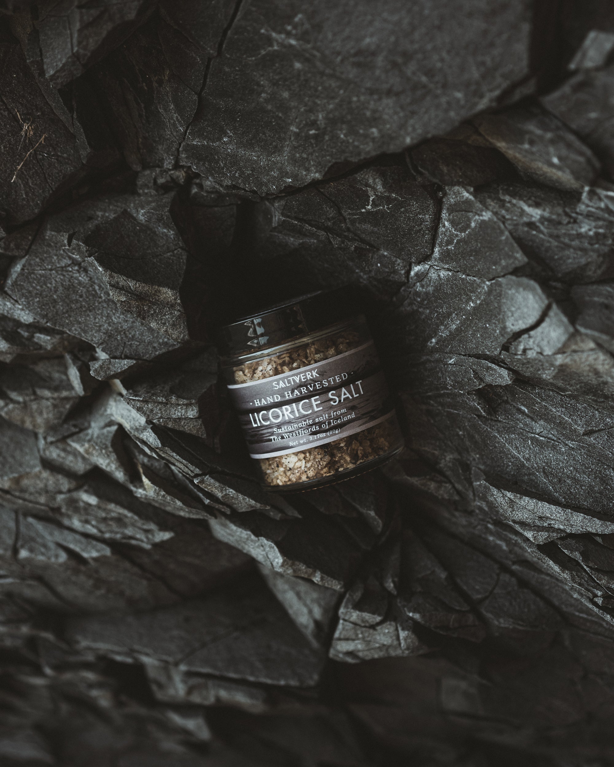 Jar of licorice salt on a dark stone surface