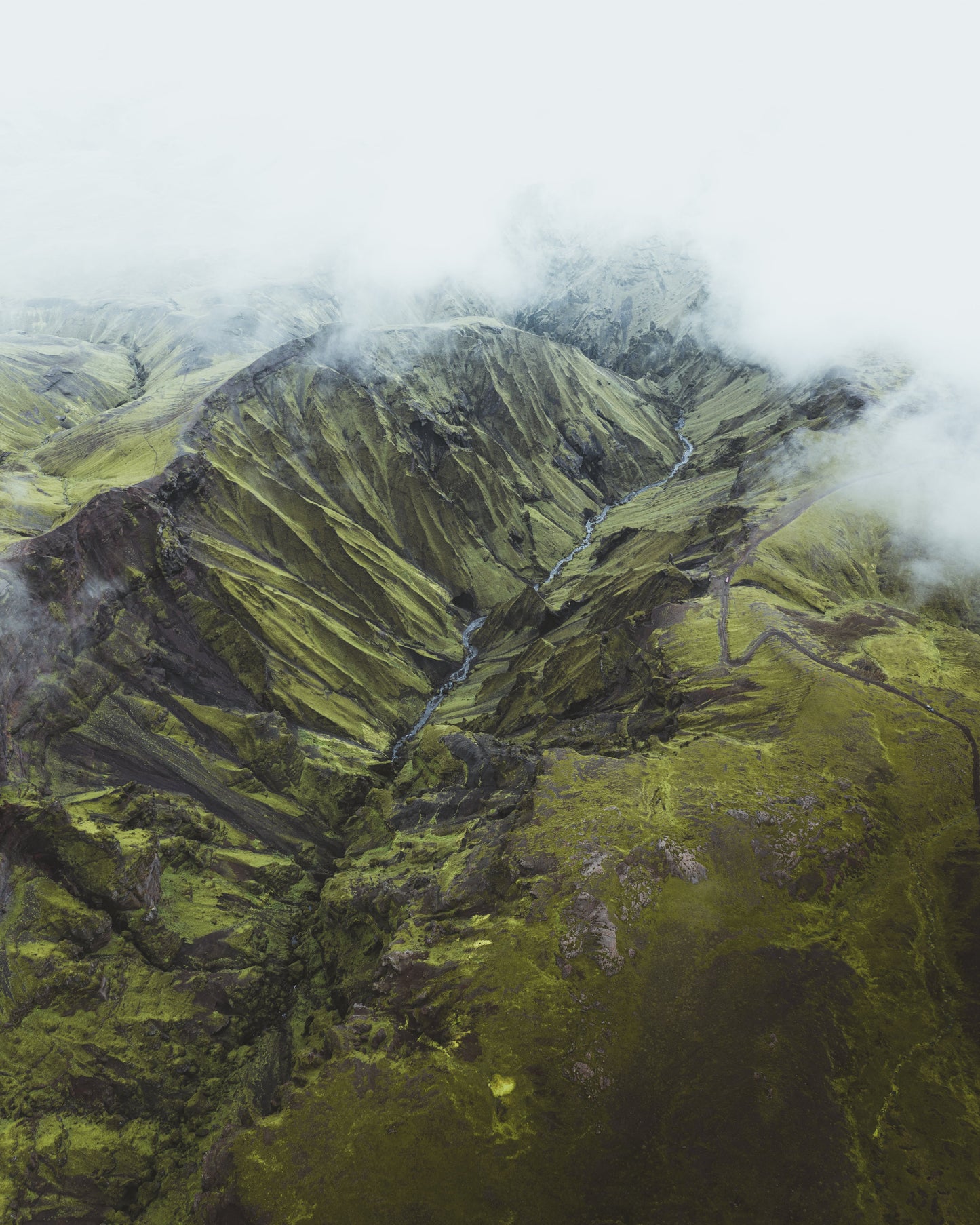 Aerial view of a mountainous landscape with green terrain and clouds.
