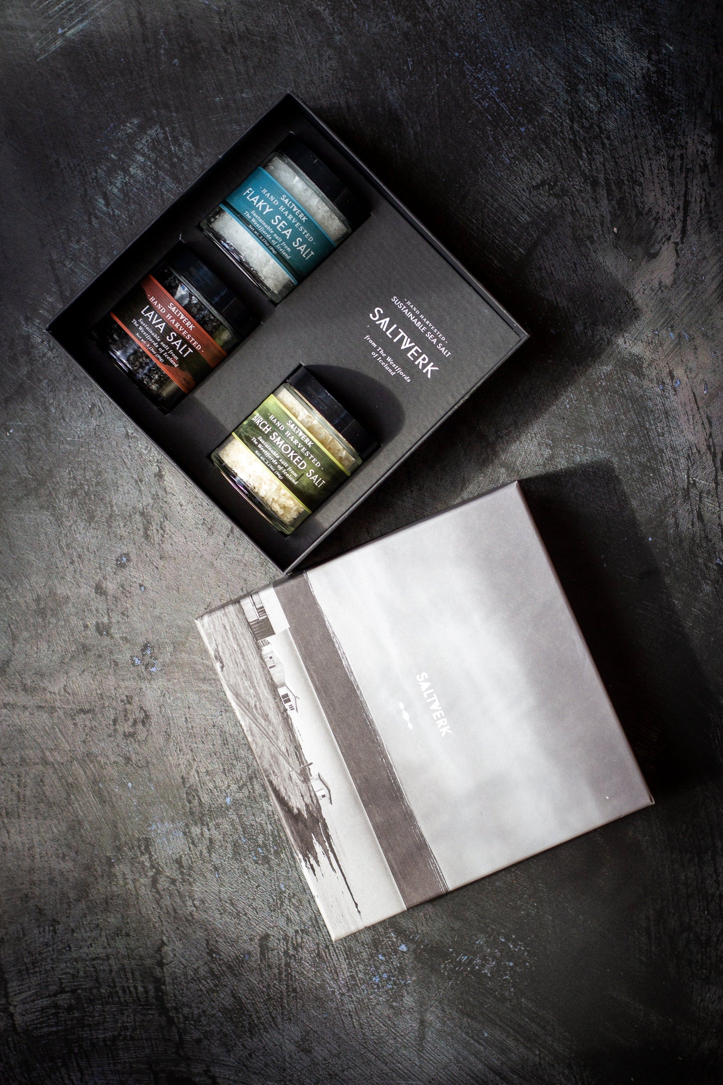 Set of small jars with a branded box on a dark surface