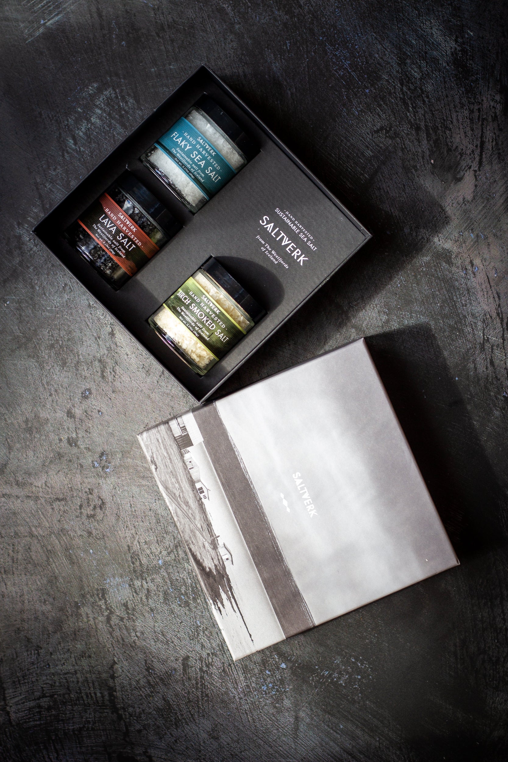 Set of small jars with a branded box on a dark surface